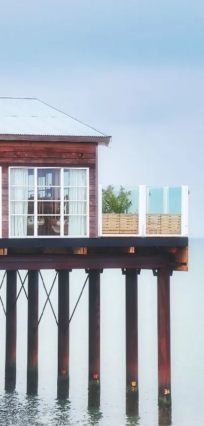 Serene seaside pier house over calm ocean water with light blue sky.