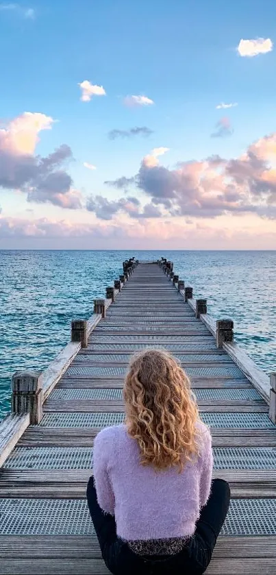 A serene wooden pier extending into a calm ocean under a pastel sky.