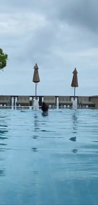 Tranquil poolside scene with ocean view and cloudy sky.