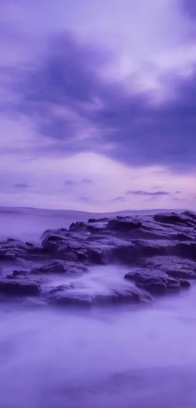 Purple ocean view with rocks under a cloudy sky.