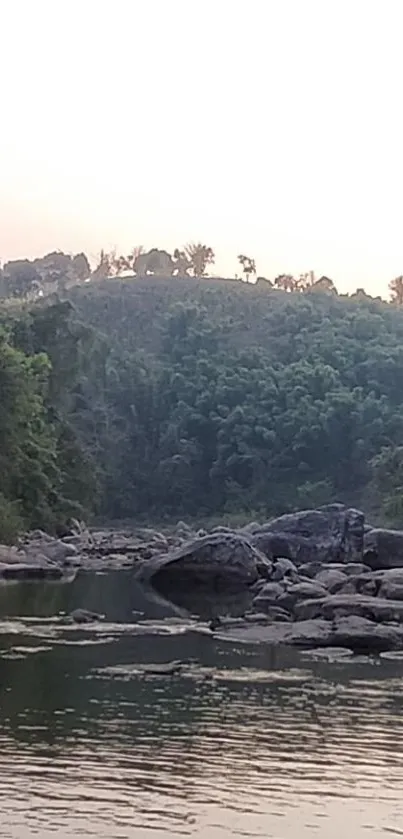 Tranquil river landscape with green hills and rocks in the foreground.