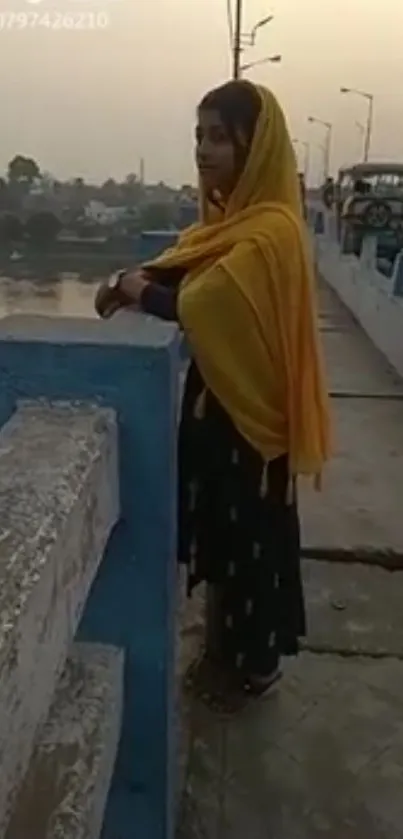 Woman in traditional dress on bridge at sunset.