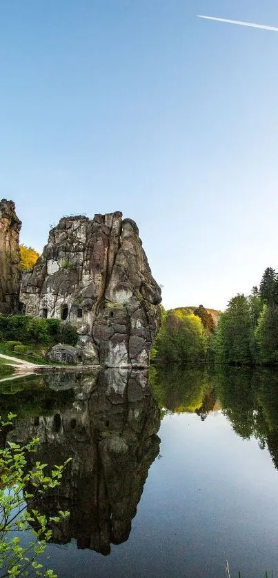 Rock formations reflected in a tranquil lake under a blue sky.