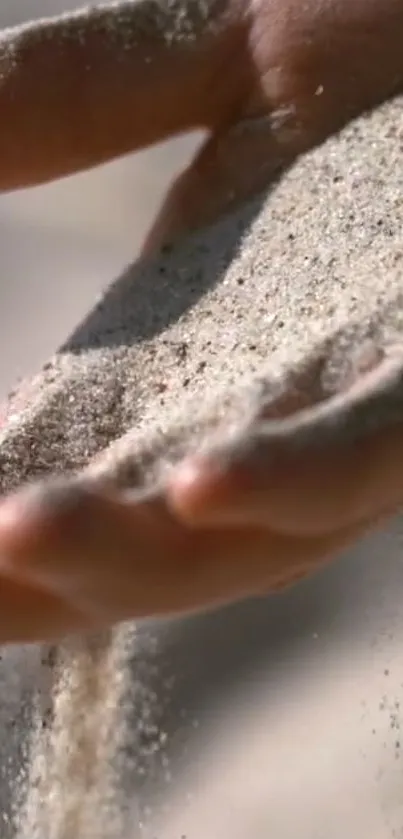 Serene wallpaper of sand flowing through hands.