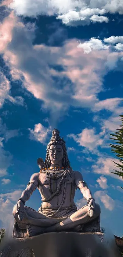 Shiva statue meditating beneath a vibrant blue sky with clouds.