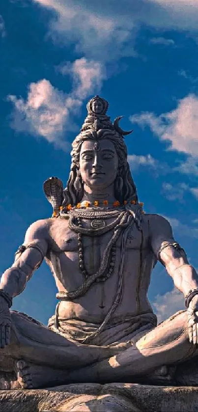 Shiva statue under vibrant blue sky, surrounded by nature.