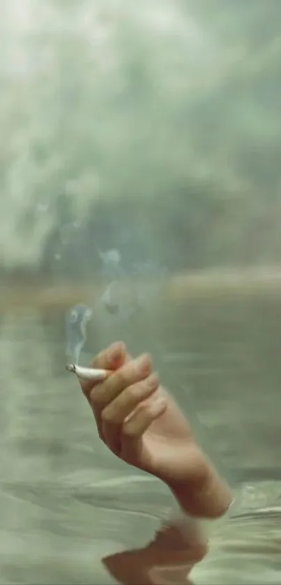 Hand holding cigarette over calm water in a soft green serene setting.