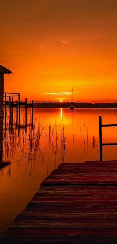 Sunset over tranquil lake with orange sky and dock.