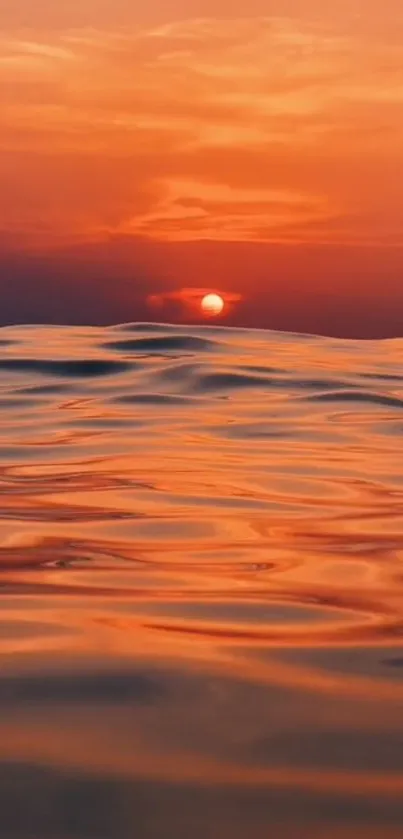 Serene sunset over ocean with orange hues.