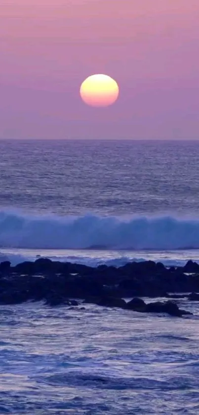 Lavender sunset over ocean with waves and rocks.