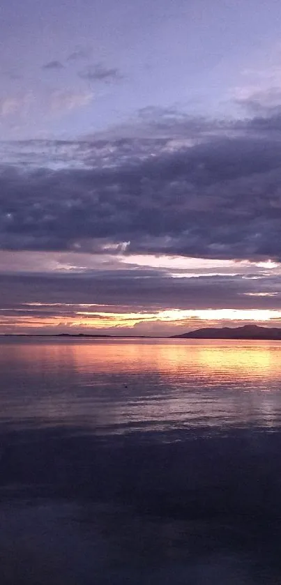 Tranquil sunset over ocean with purple skies and serene reflection.