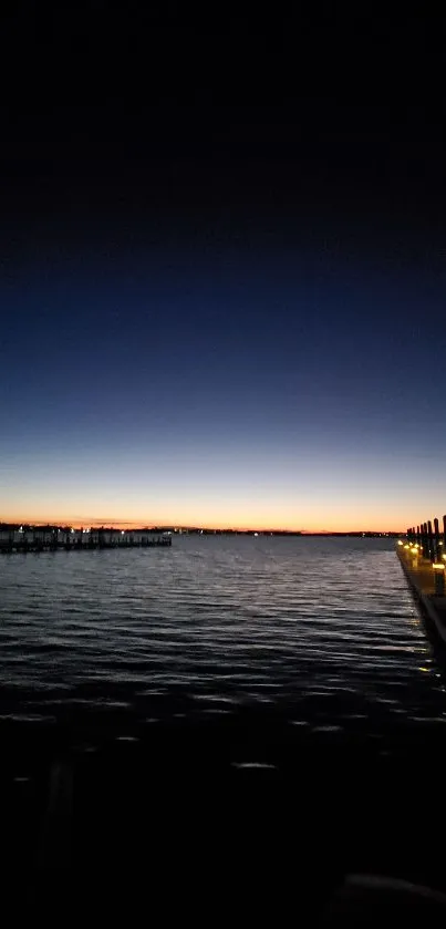 Serene sunset over a dark pier with a radiant horizon.