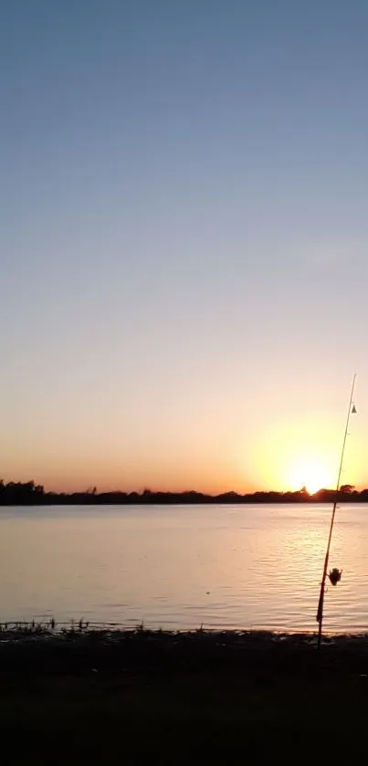 Tranquil sunset over calm water with fishing in the foreground.