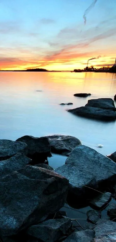 Sunset over rocky shore with blue sky.