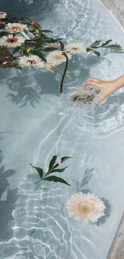 A hand reaches for flowers floating on clear water under a bright sky.