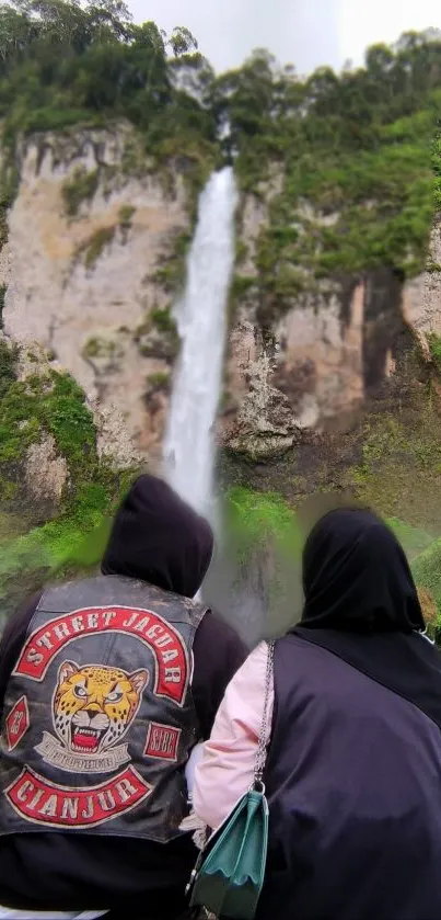 Waterfall with greenery and two adventurers enjoying the view.