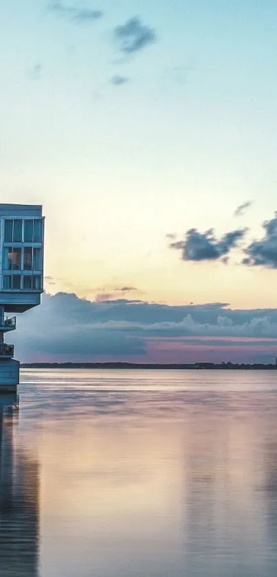 Waterfront sunset with pastel skies and modern building reflecting on calm water.