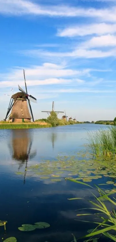 Tranquil windmills reflect on a peaceful river under a vibrant blue sky.