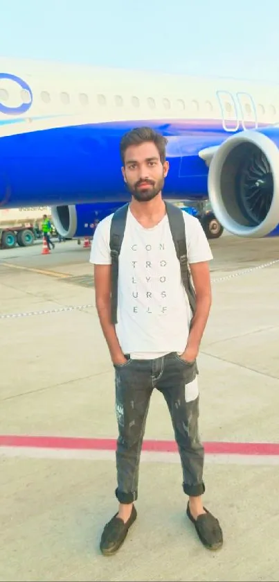 Traveler standing by a blue plane on the airport runway.