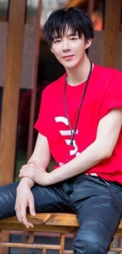 Young man in a stylish red shirt sitting on a wooden bench.