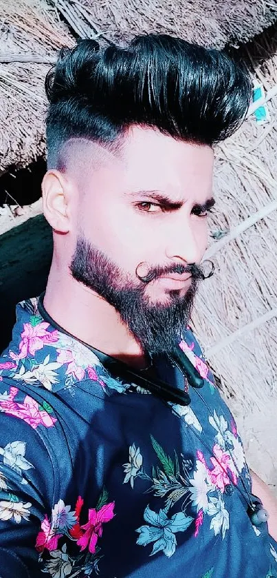 Man in floral shirt posing outdoors with stylish hair and beard.