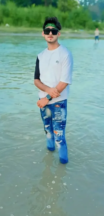 Young man in trendy fashion standing in water.