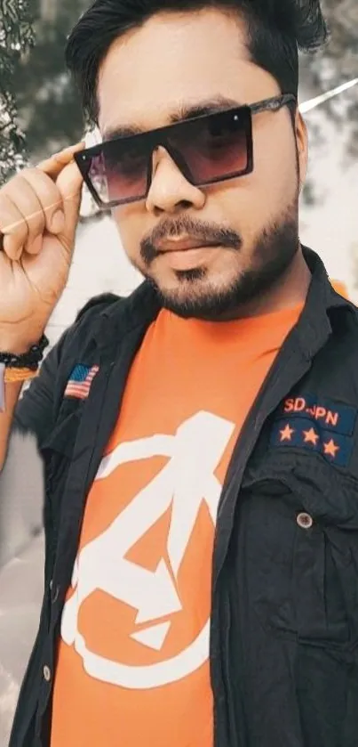 Cool man wearing sunglasses and an orange shirt with a unique logo.