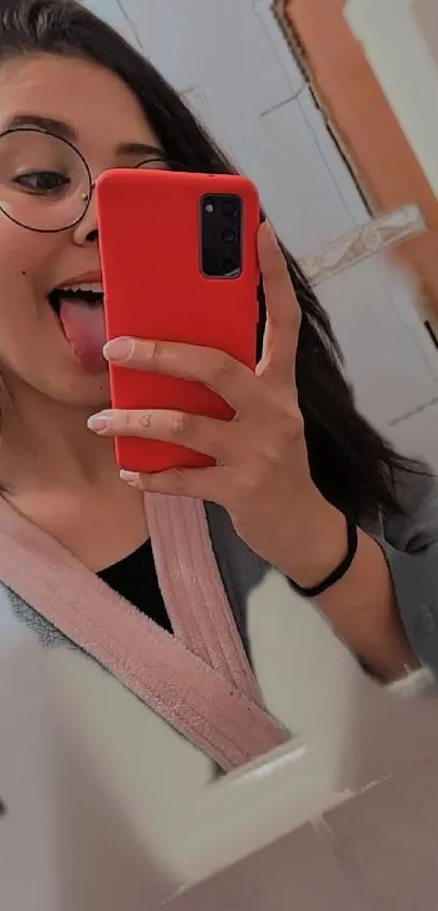 Trendy girl taking a mirror selfie with a red phone.