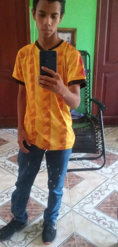Young person in vibrant geometric t-shirt taking a mirror selfie.