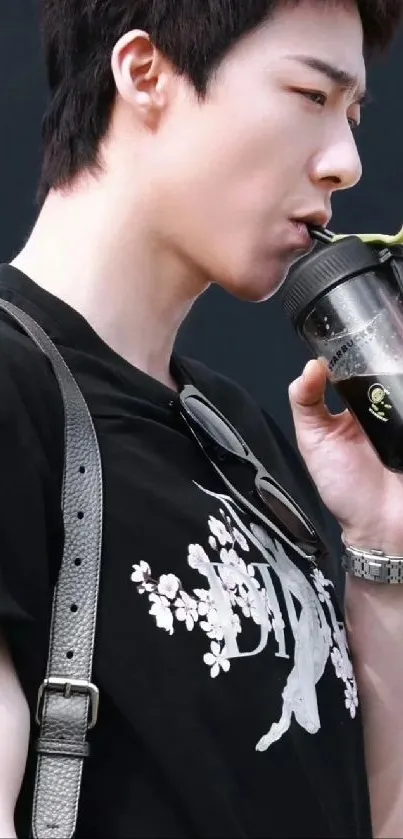 Modern young adult in black shirt with drink bottle on dark background.