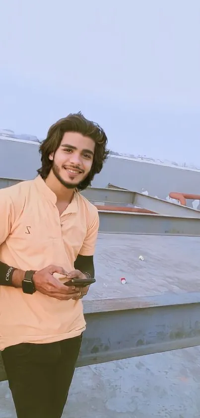 Young man smiling outdoors with sky blue background.