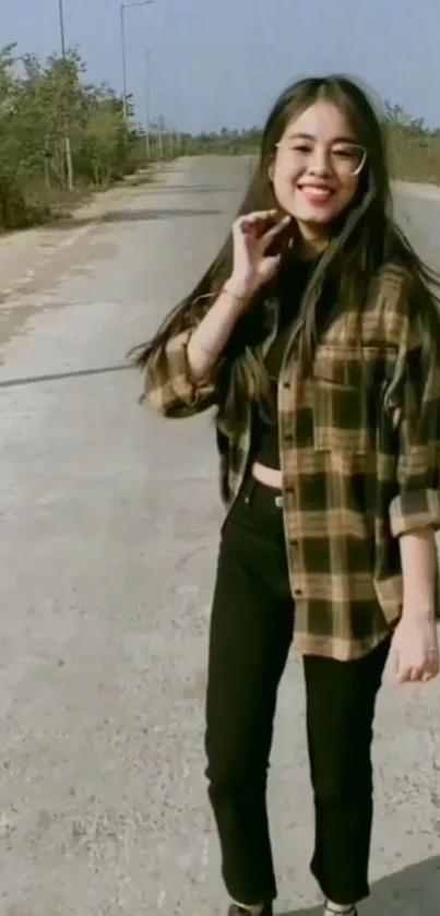 Young woman in checkered shirt on sunny road.