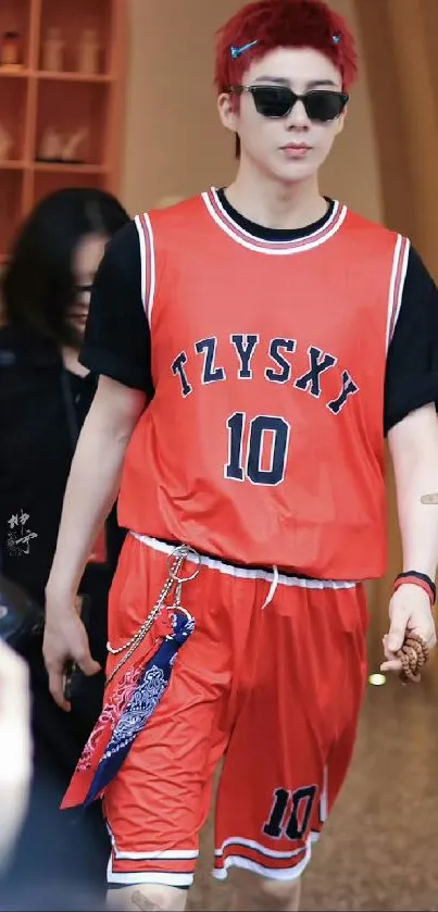 Person in red basketball outfit with sunglasses on street.