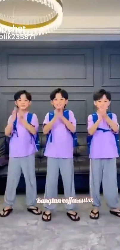 Three children in matching outfits standing indoors in a modern living room.