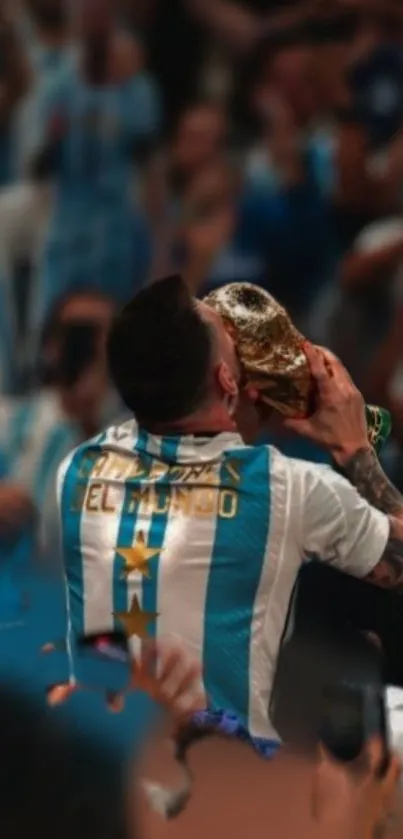 Soccer player kisses trophy in victory celebration, light blue jersey.