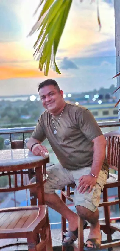 Man enjoying tropical sunset on a balcony with chairs.