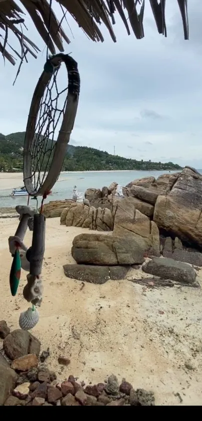 Dreamcatcher under palm on tropical rocky beach.