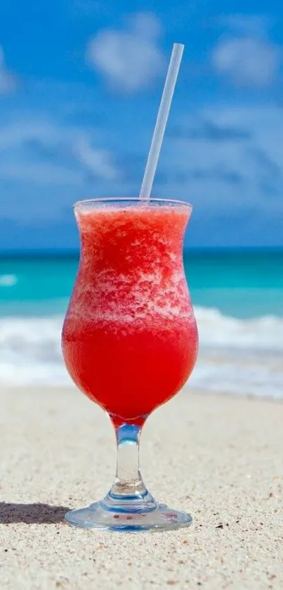 Refreshing tropical drink on a sandy beach with blue ocean and sky.