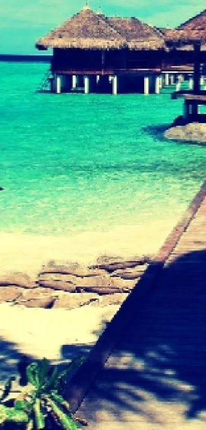 Tropical beach with turquoise water and wooden pier leading to huts.