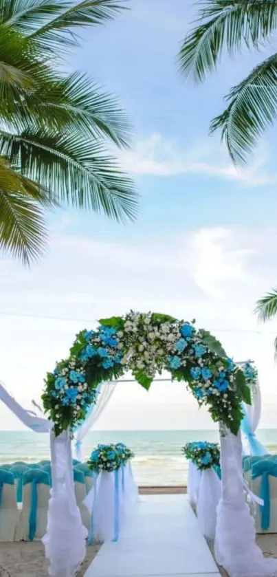 Tropical beach wedding with floral arch under palm trees and clear blue sky.