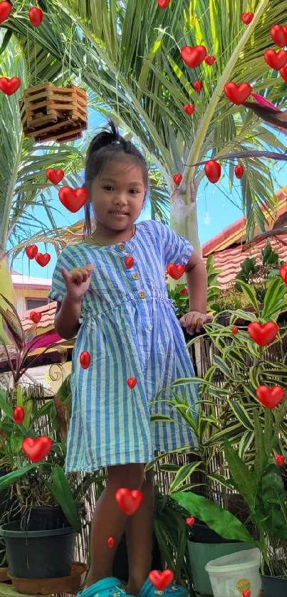 Young girl in blue dress surrounded by tropical plants in a garden setting.