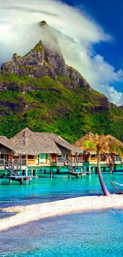 Tropical island with bungalows surrounded by clear blue water and lush mountains.