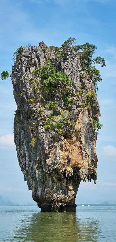 Tropical island with towering rock formation under a bright blue sky.