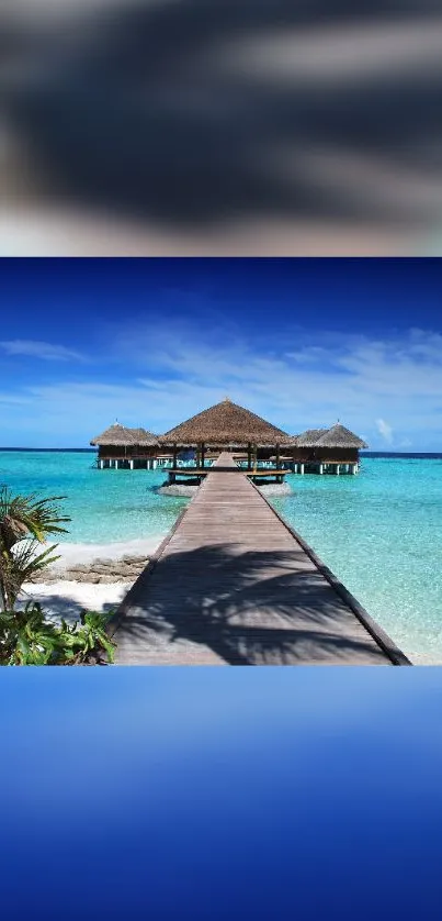 Tropical beachfront with turquoise sea and wooden pier under clear sky.