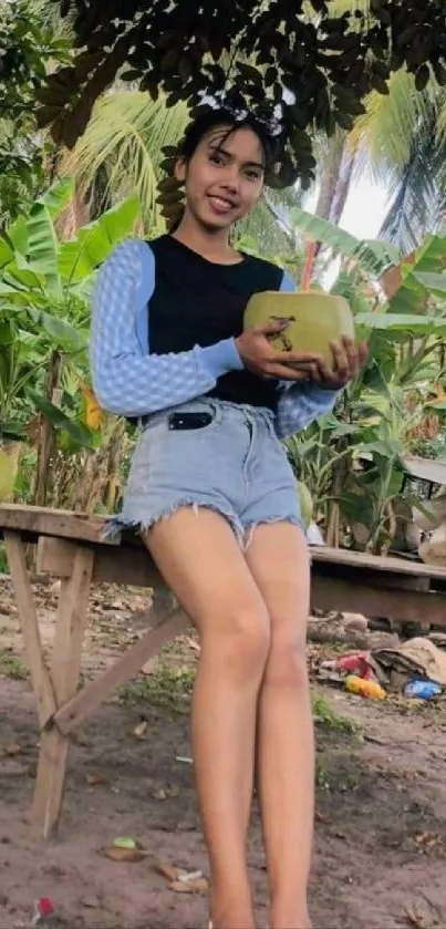 Woman in a tropical garden holding a coconut, surrounded by lush greenery.