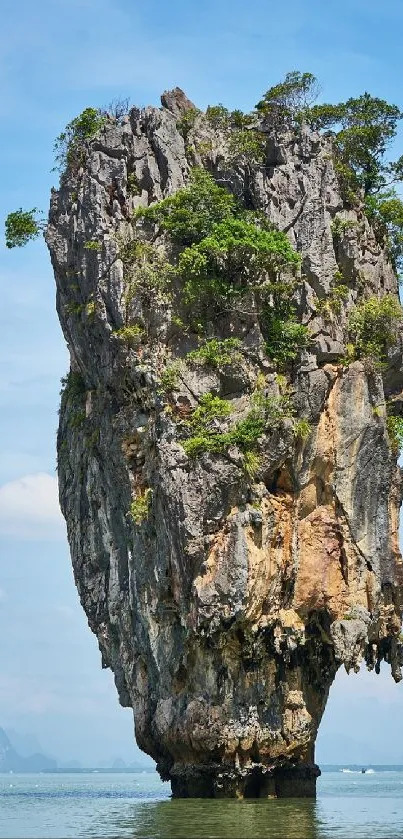 Tropical rock island standing in the ocean under a vibrant blue sky.