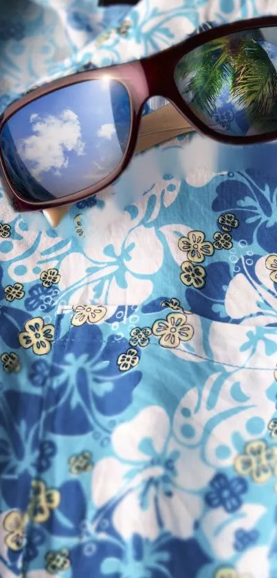 Tropical sunglasses on blue floral Hawaiian shirt with cloud reflections.