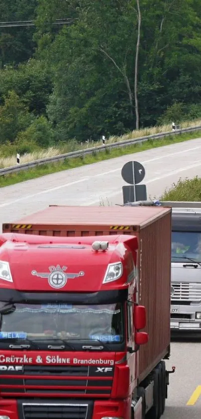 Red and silver trucks on a tree-lined highway.