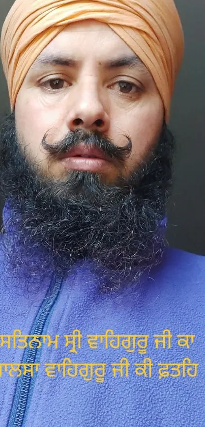 Man with an orange turban and blue jacket against a neutral background.