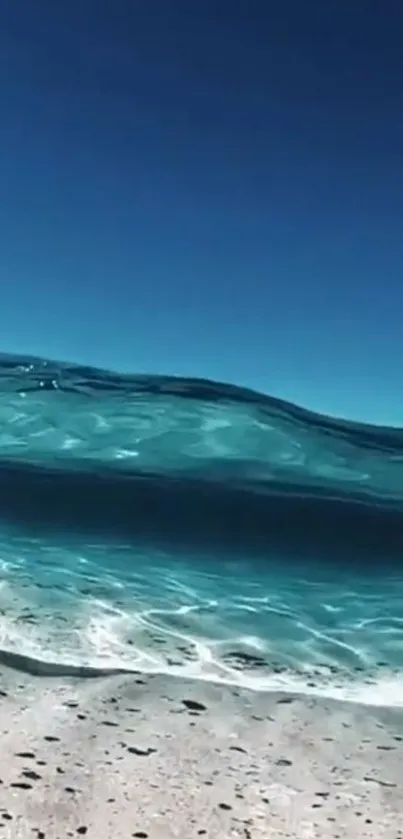 Turquoise ocean waves meeting a sandy beach under a clear sky.